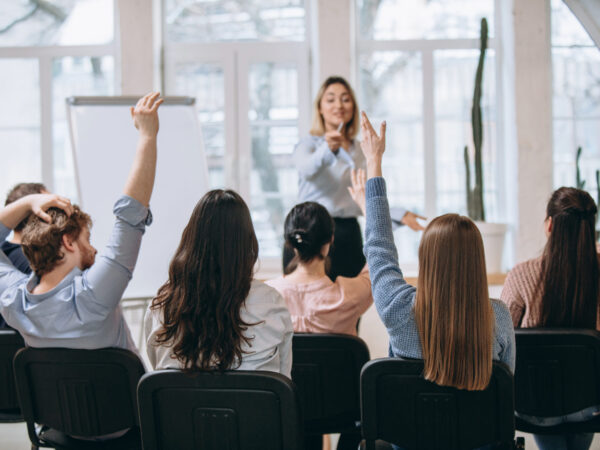 Increase. Female speaker giving presentation in hall at university workshop. Audience or conference hall. Rear view of unrecognized participants. Scientific, business event, training. Education